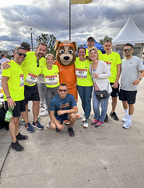 Group of Avient employees posing with mascot at a race