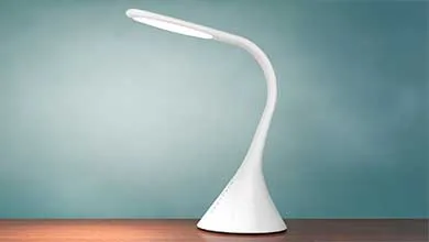 White gooseneck desk lamp with a conical base on a wooden surface against a teal wall.