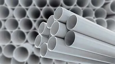 Close-up of a small bundle of light gray pipes, with a large, blurred stack of pipes in the background.