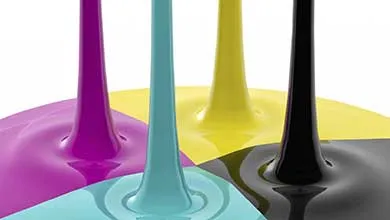 Streams of glossy liquid colorants in purple, teal, yellow, and black flowing downward onto a smooth surface.