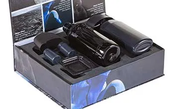 Premium product packaging box opened to reveal black cosmetic containers arranged in custom foam inserts.