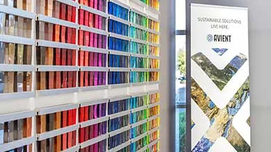 Interior wall display of color samples arranged in vertical rows, with an Avient sustainability banner nearby.