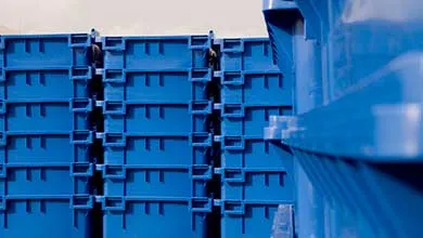 Stacked bright blue plastic storage crates with ribbed, rectangular reinforced surfaces and a glossy finish.